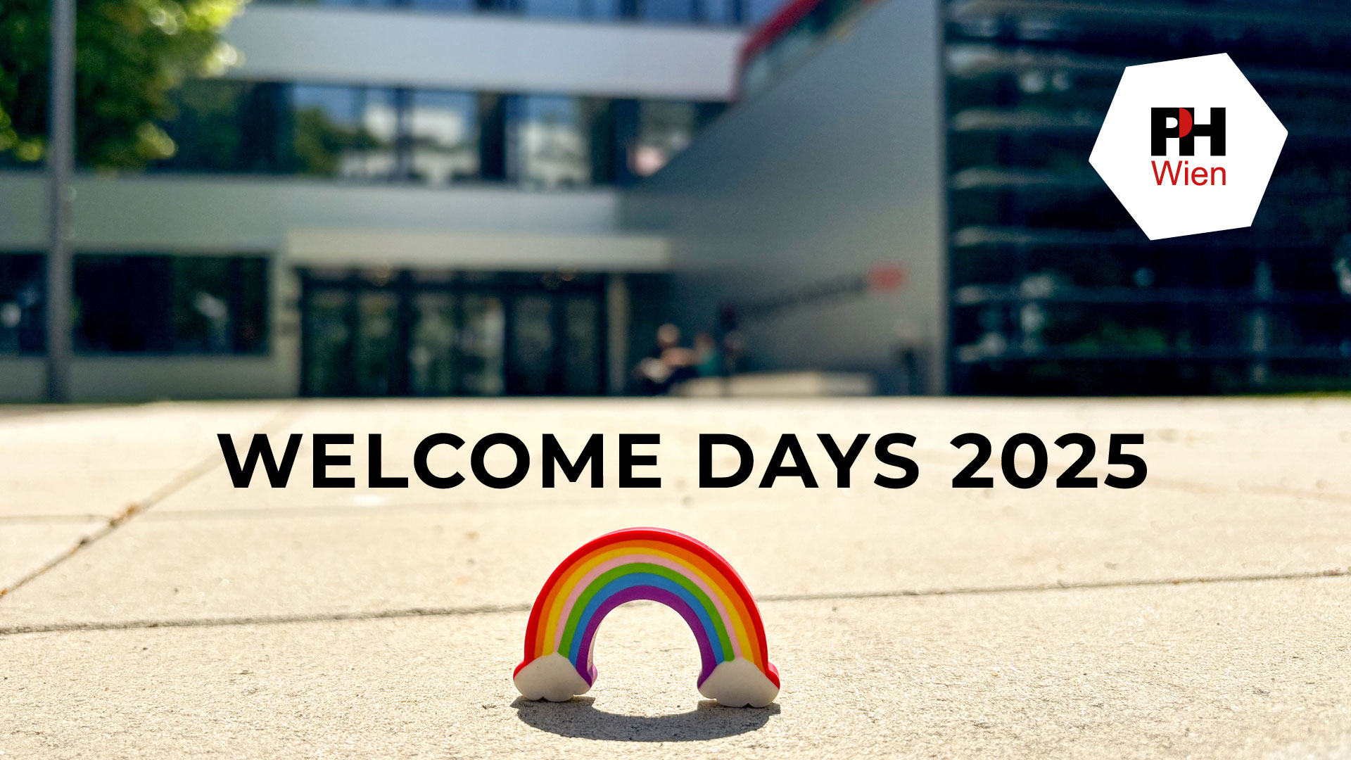 Schriftzug "Welcome Days 2025" auf einem verschwommenen Bild des Hauseingangs der Pädagogischen Hochschule Wien